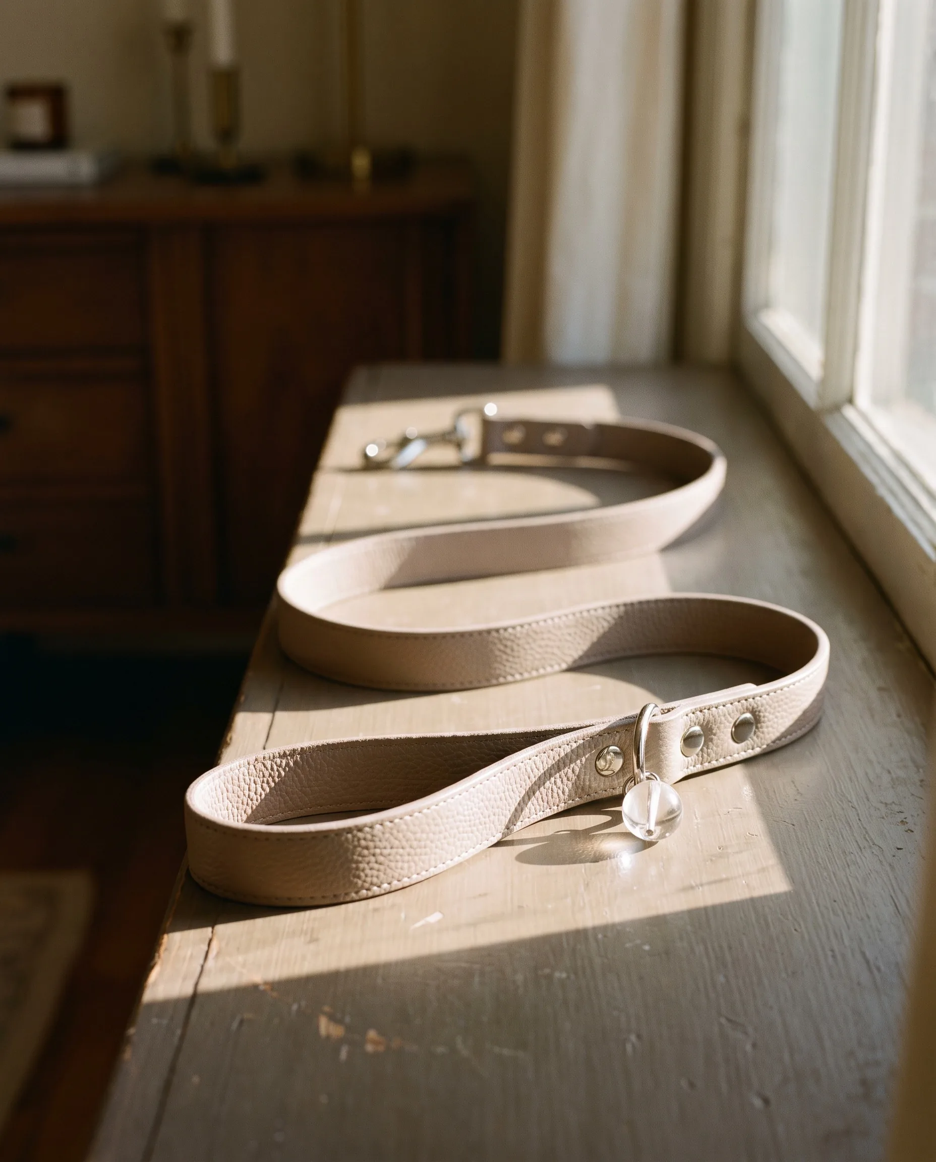 Taupe LuKra leash with a clear quartz stone on a sunlit windowsill
