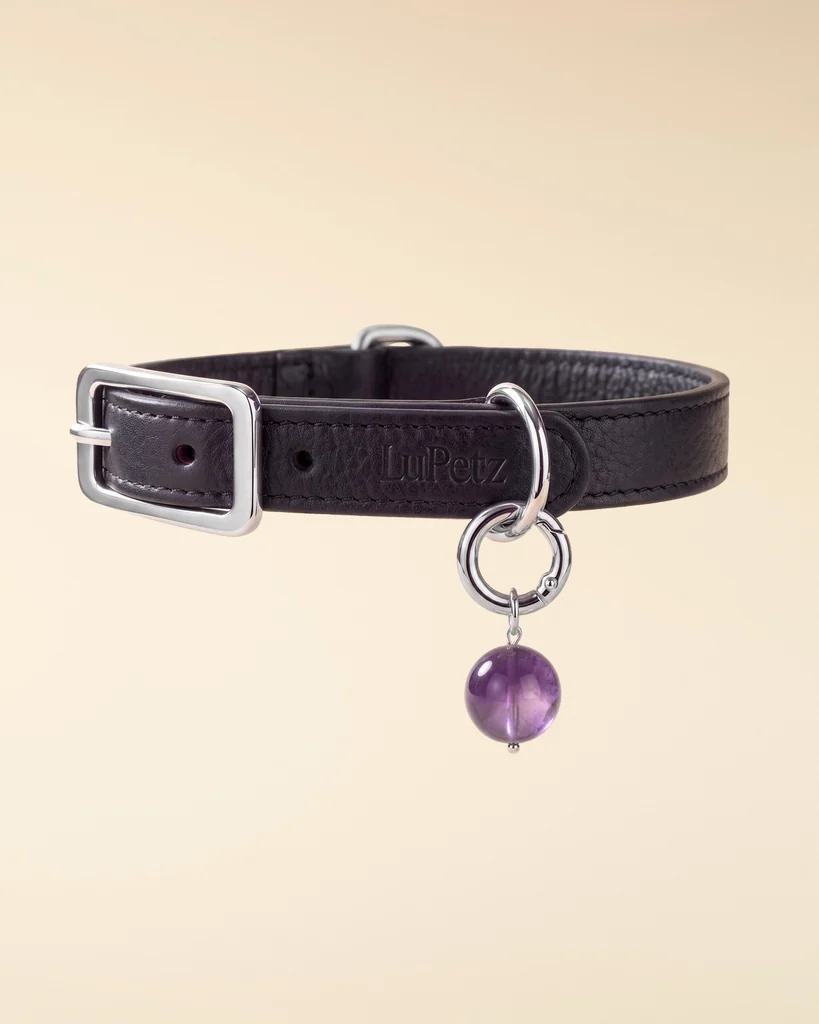 Black leather LuKra collar with an amethyst bead on a pale background