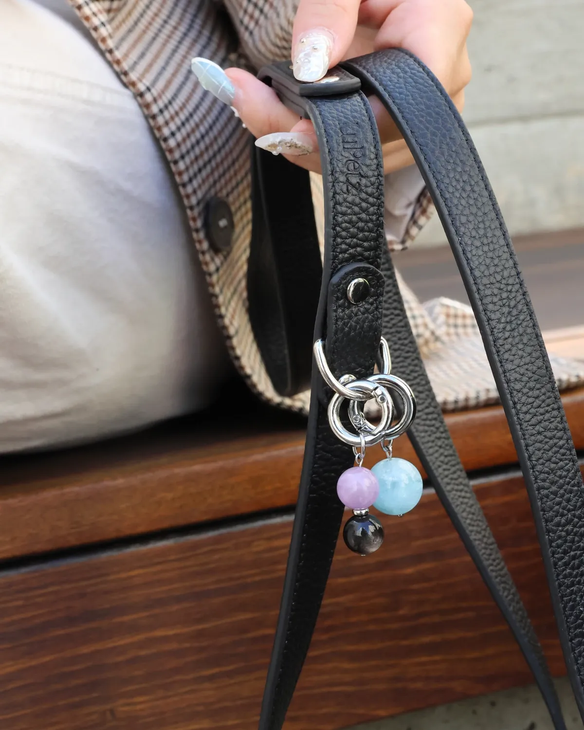 Hand holding a black LuKra leash with rose quartz, aquamarine and obsidian beads