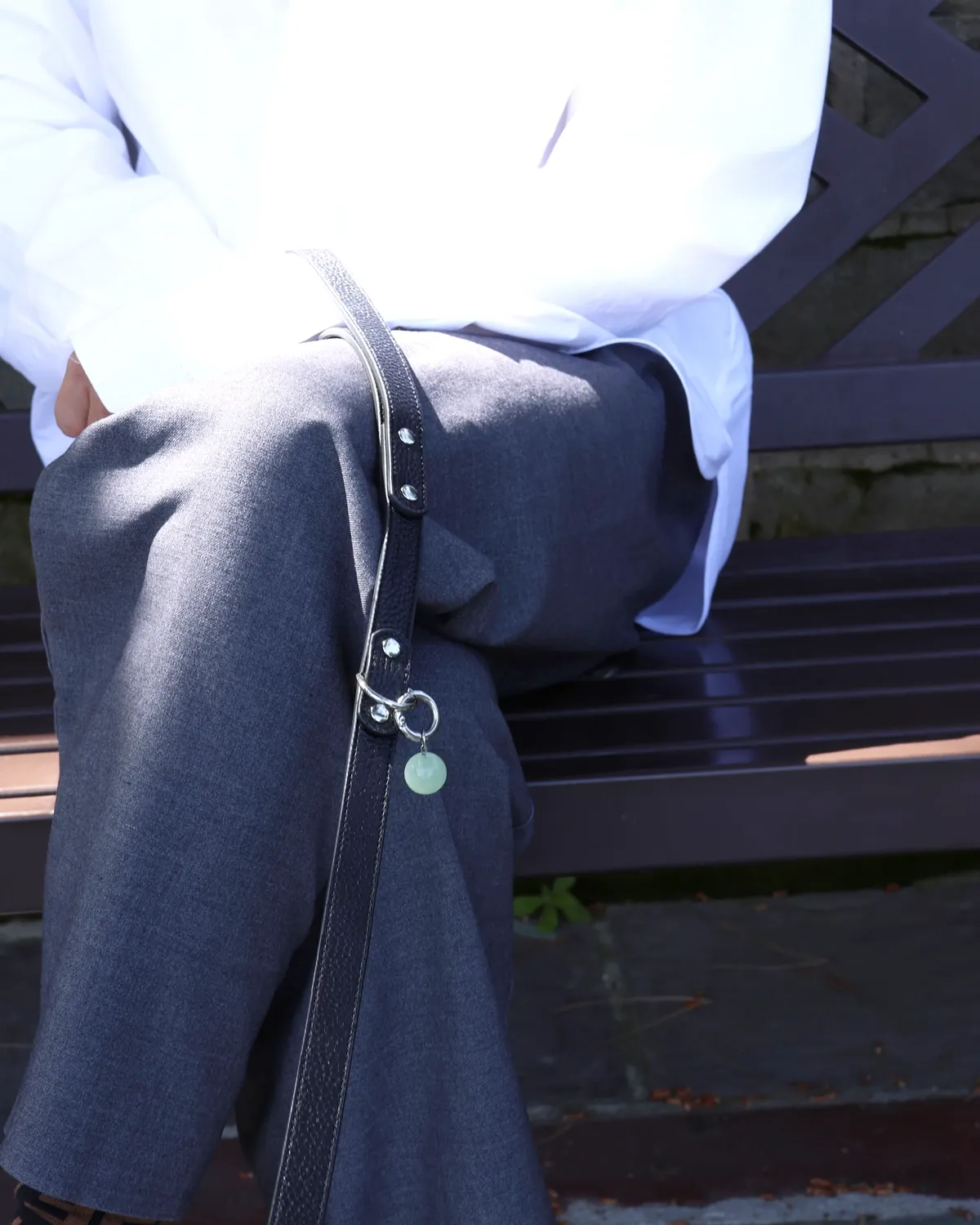 Person on a bench holding a black LuKra leash with a green aventurine bead