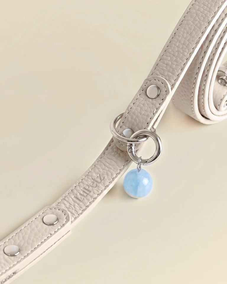 Close-up of a taupe leather LuKra leash with an aquamarine bead by the clip